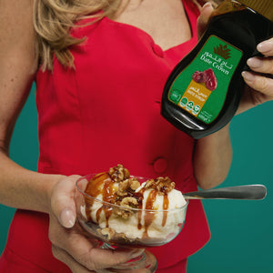 Person holding a dessert with a bottle of syrup against a teal background